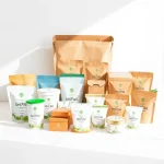 A professional product display of Uni-Pak packaging solutions, showing various types of high-quality, eco-friendly packaging materials such as corrugated boxes, flexible pouches, and rigid containers arranged neatly on a clean white surface, with subtle branding elements and soft natural lighting to emphasize product quality and sustainability